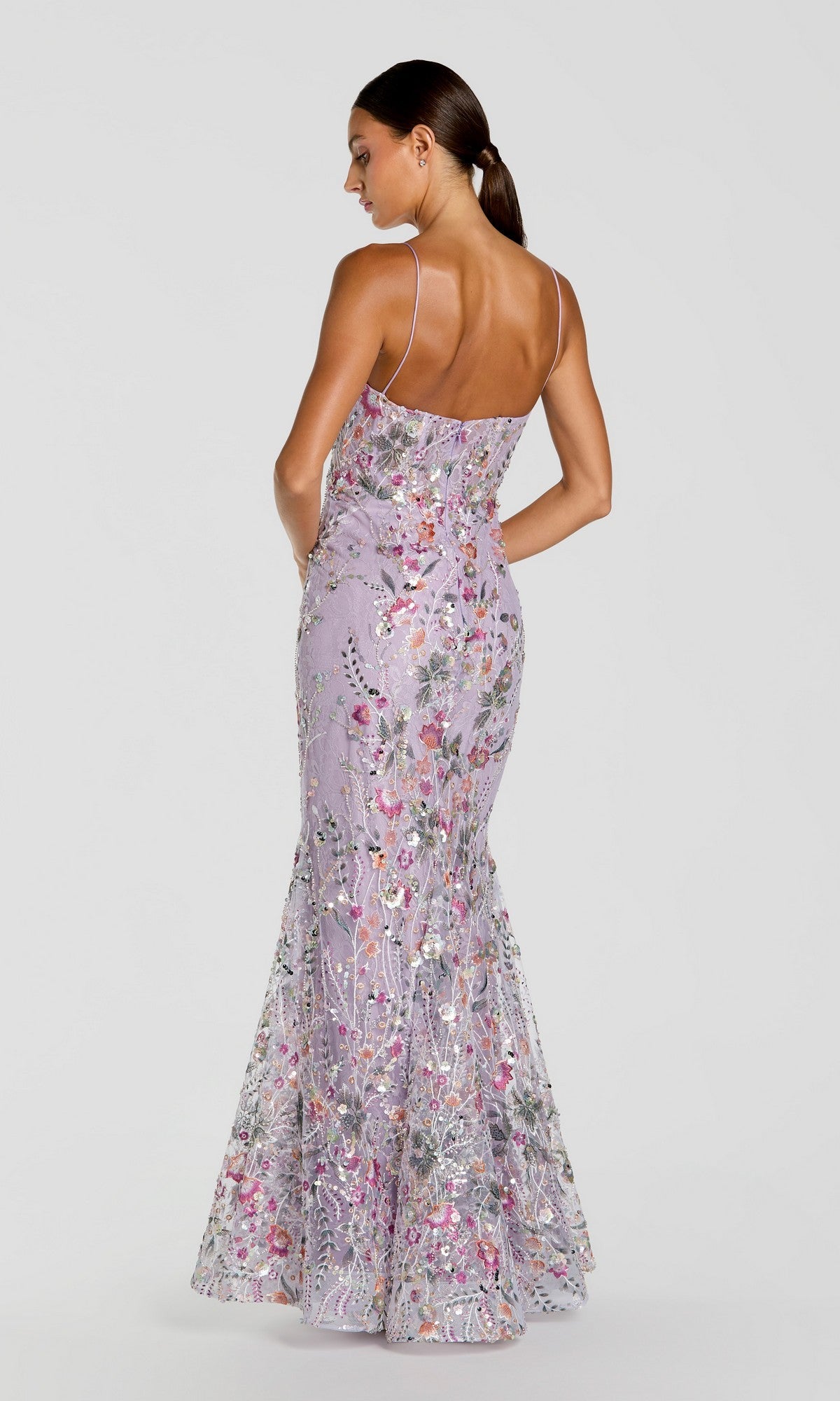A woman stands with her back to the camera against a plain background, wearing the Mac Duggal 69049 Long Formal Dress—a fitted lilac gown adorned with thin straps, delicate floral embroidery, and shimmering sequins.